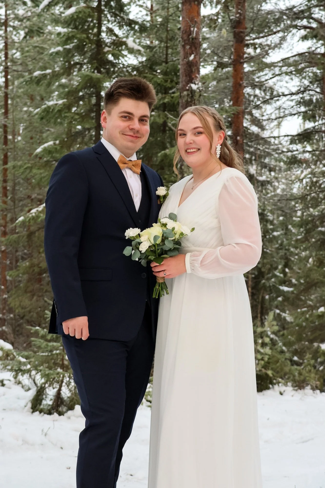 Hääparin potretti metsässä lumisella alueella.