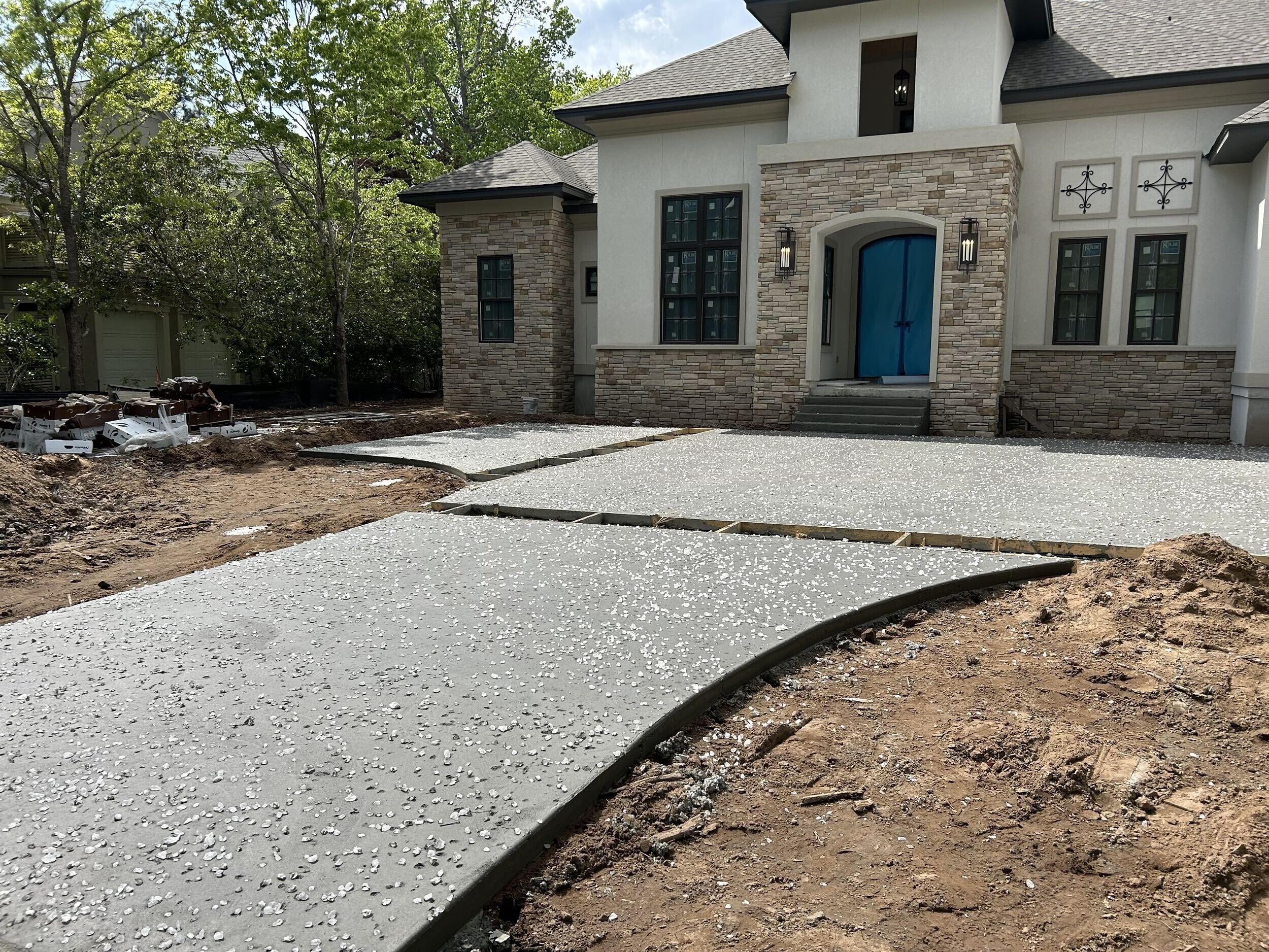 Newly poured concrete driveway in front of a modern house under construction.