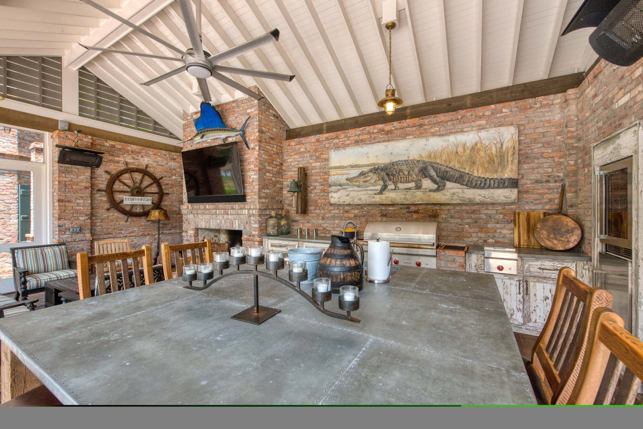 Interior of a rustic kitchen or dining area with exposed brick walls, a large metal table, wooden chairs, and decorative maritime and animal artwork and items.