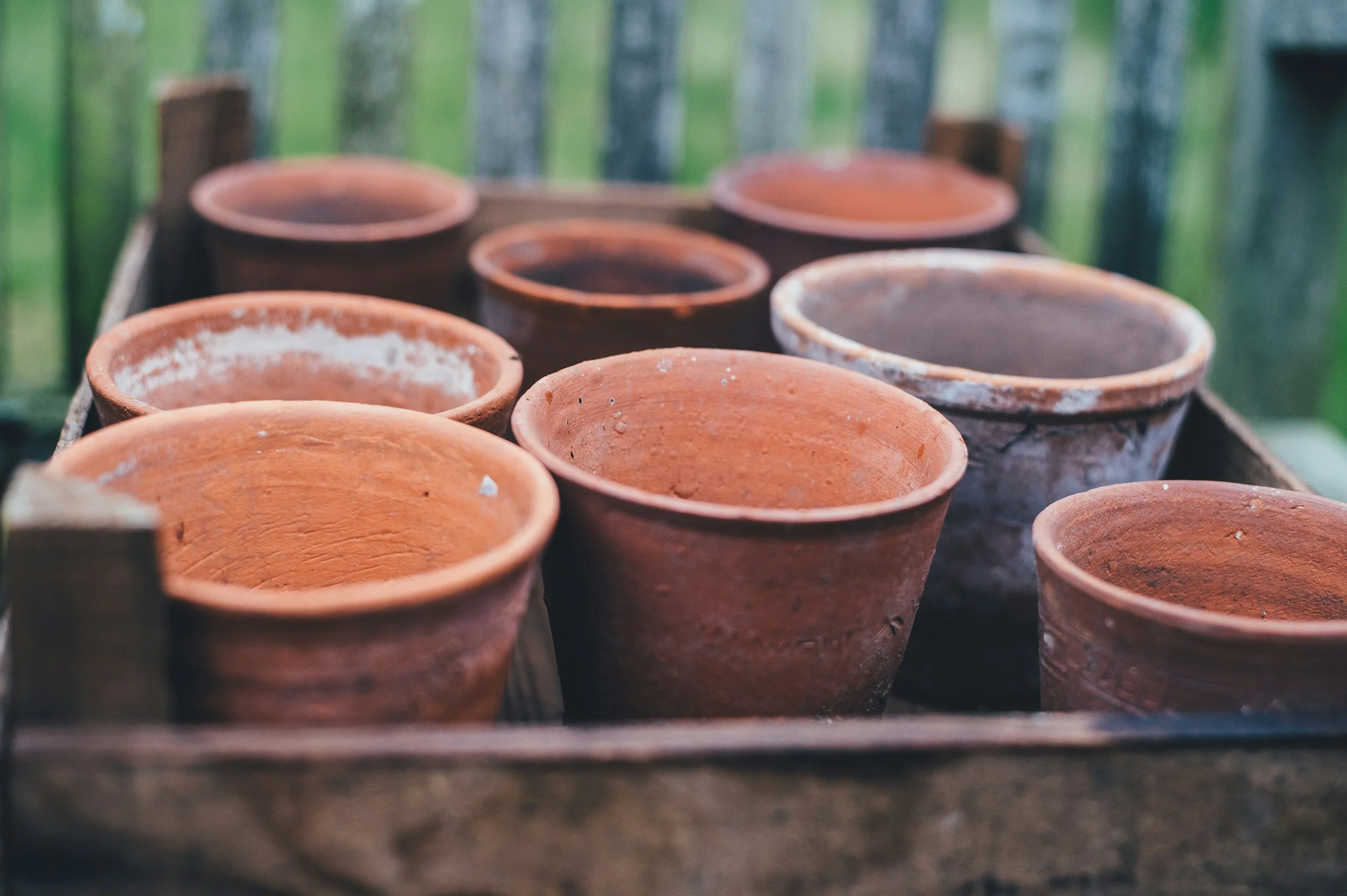 Several empty terracotta flowerpots placed on a wooden surface outdoors.