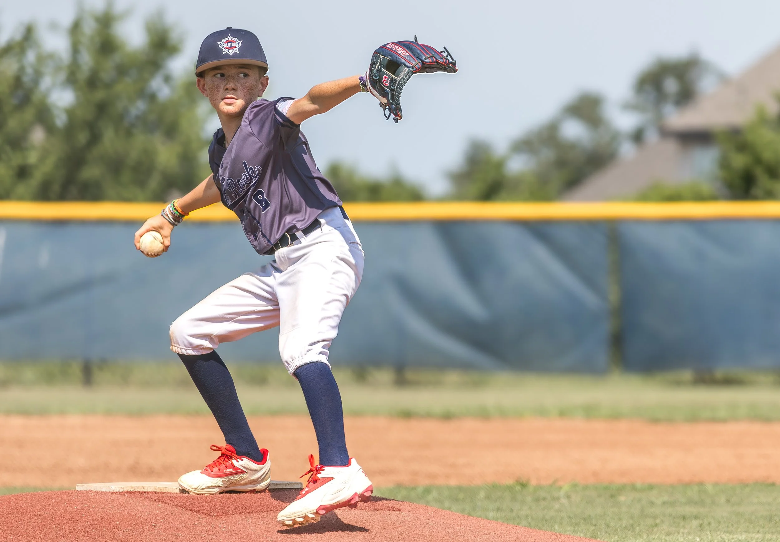 Young boy in baseball uniform pitching a ball on the field