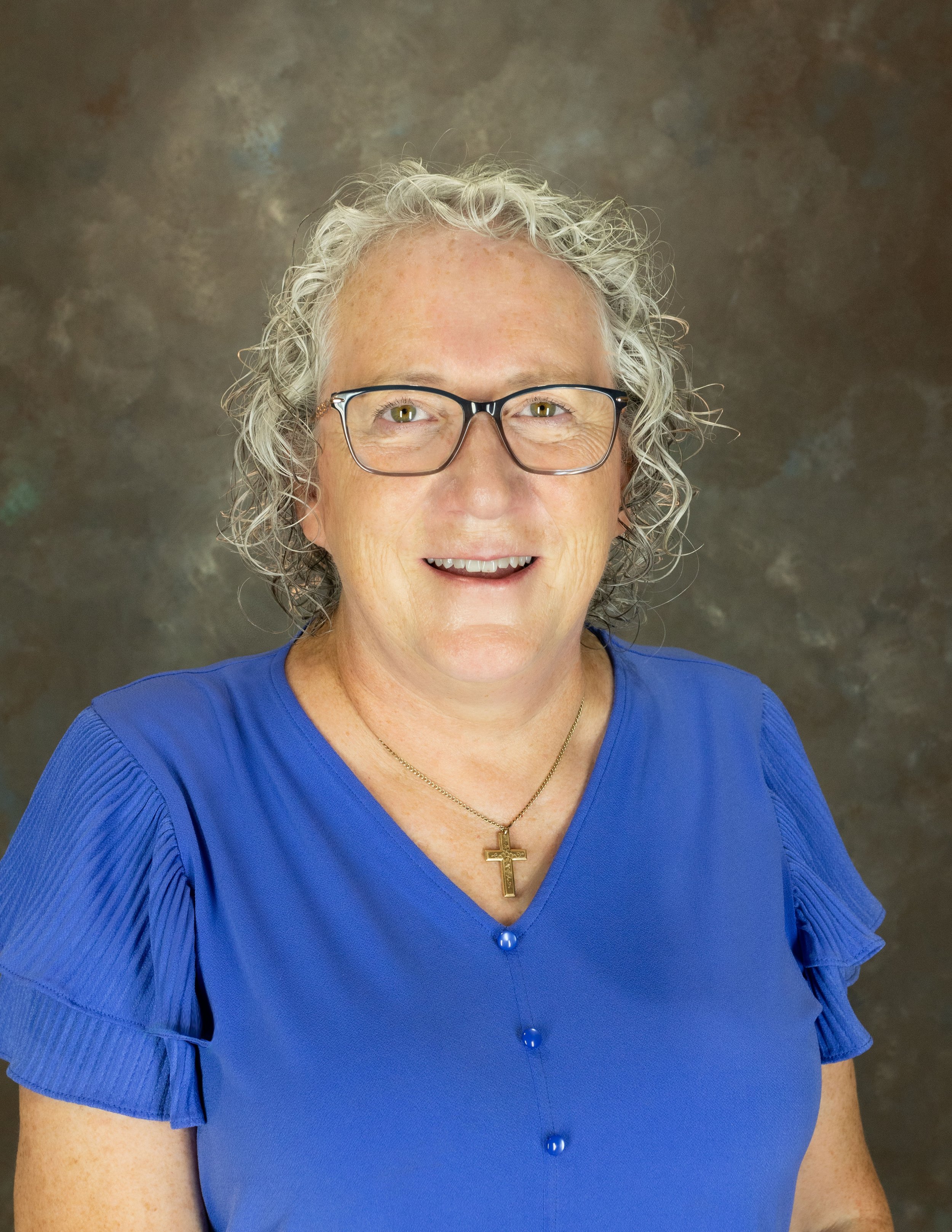A woman with curly gray hair smiling at the camera.
