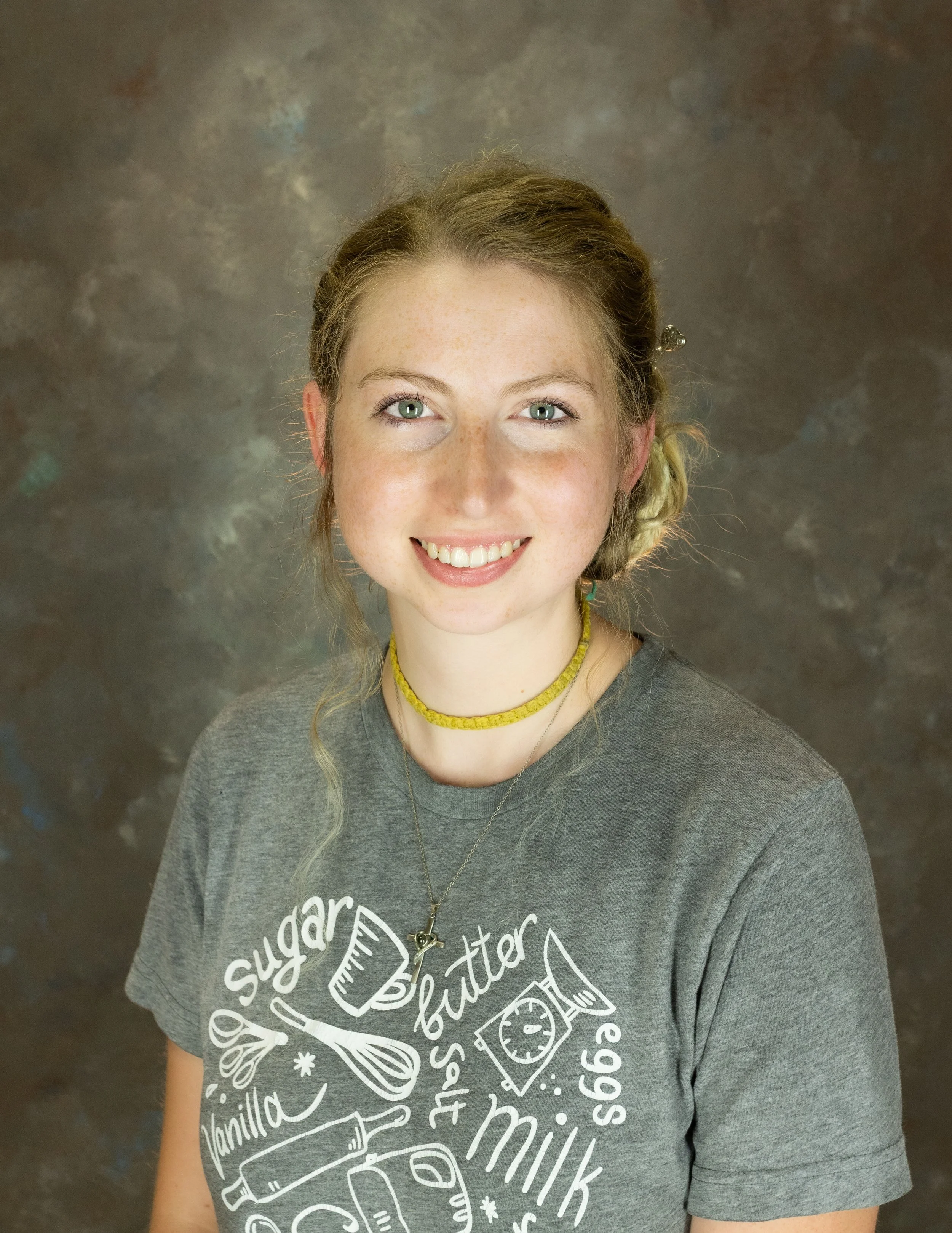 A young woman with blonde hair against a dark, textured background.