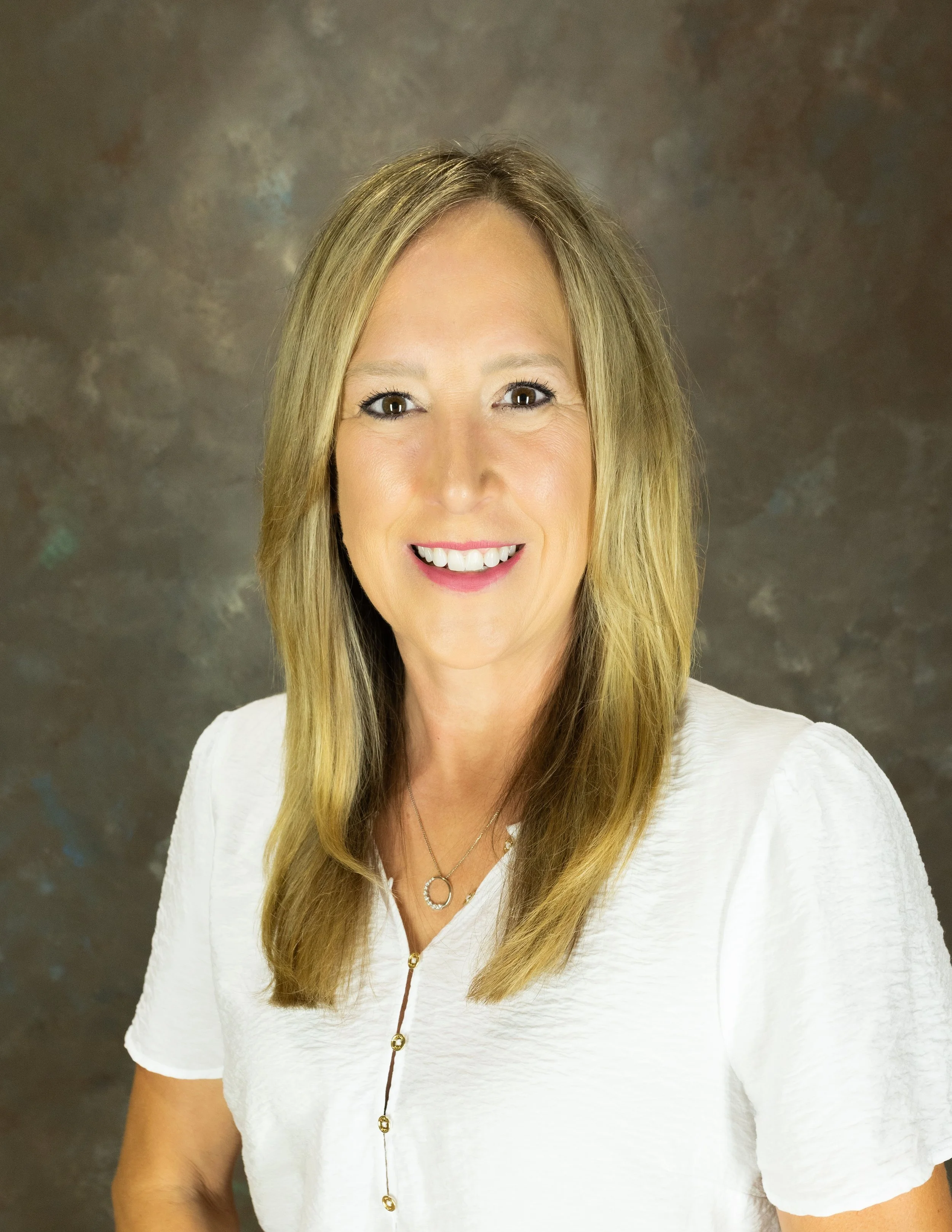 A woman with blonde hair and a white shirt.