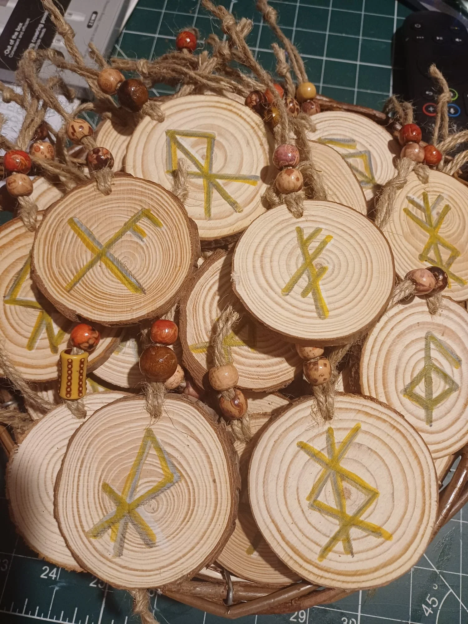 Multiple wooden discs with runic symbols, decorated with beads and hanging strings, arranged in a basket.