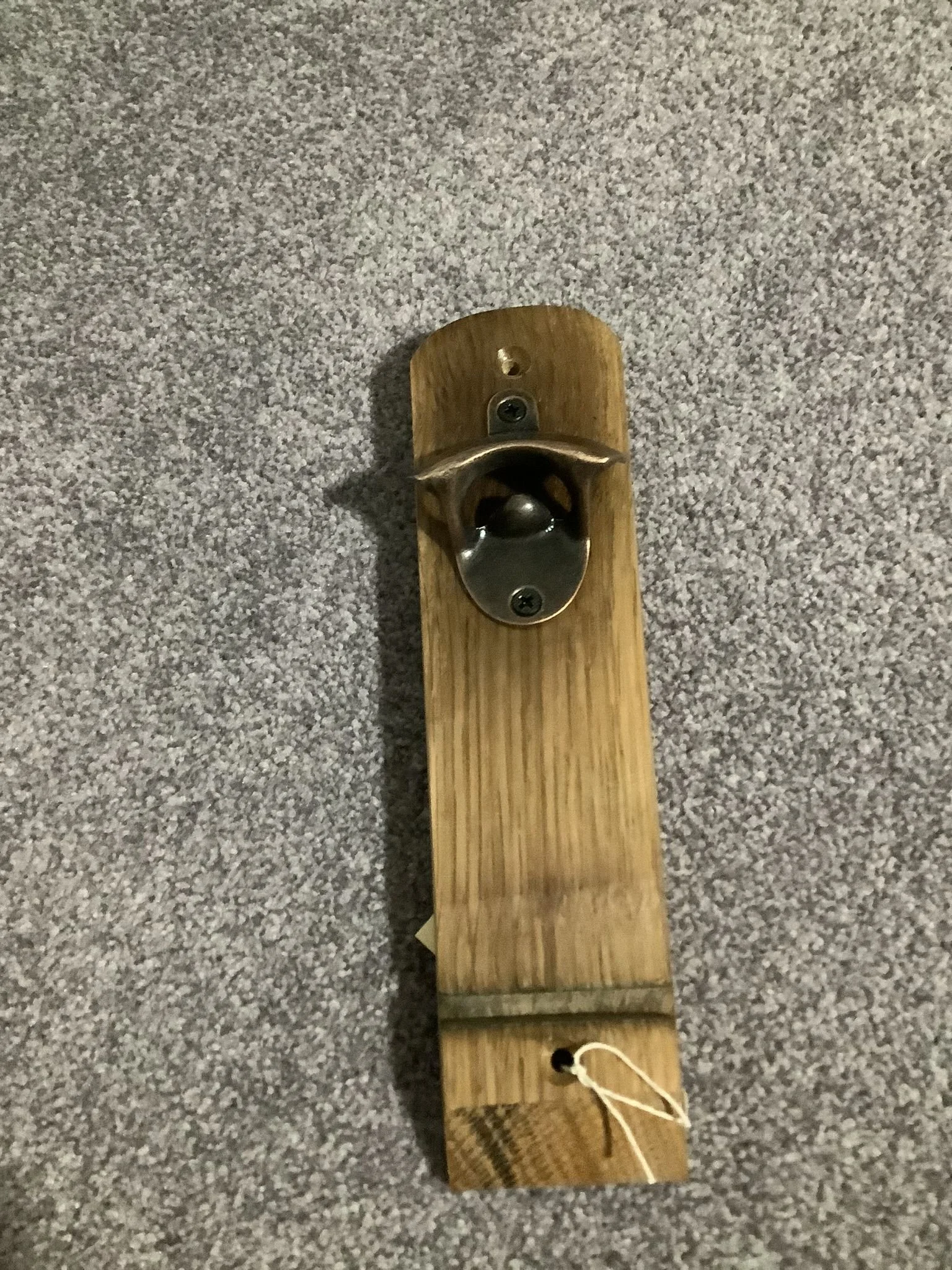 A wooden slide with a metal scoop and a handle at the top, placed on a carpeted floor.