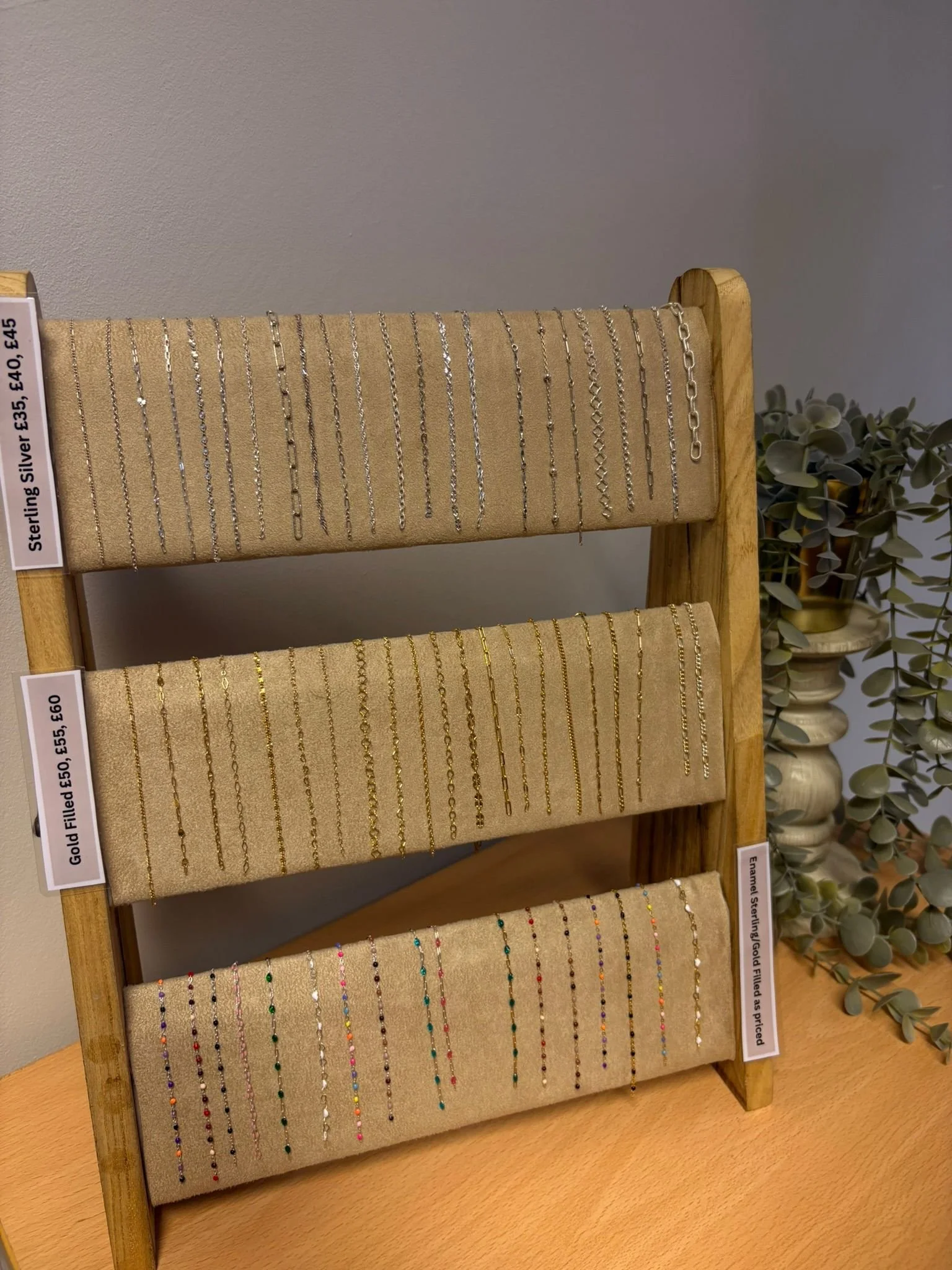 Display stand with three rows of various silver, gold, and colorful necklaces.