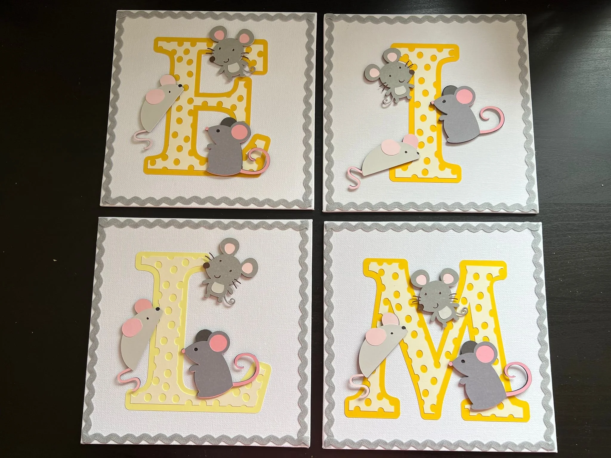 Four decorated pages with large yellow and white polka dot letters E, L, M, and V. Each letter is adorned with paper mice and mice cutouts, creating a playful, mouse-themed design for a craft project or decoration.