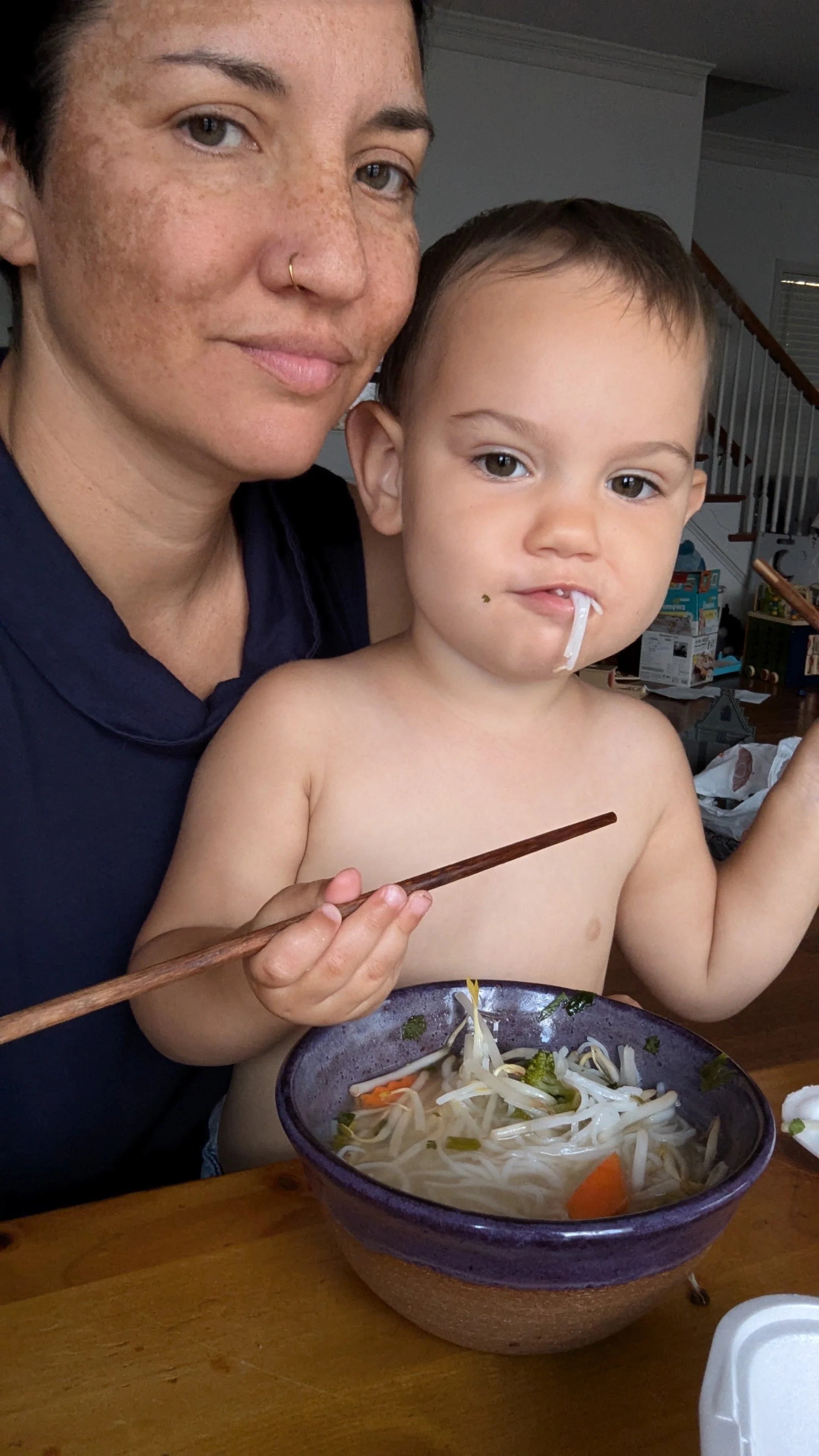 Jen Fox holding Zia while she eats Ramen