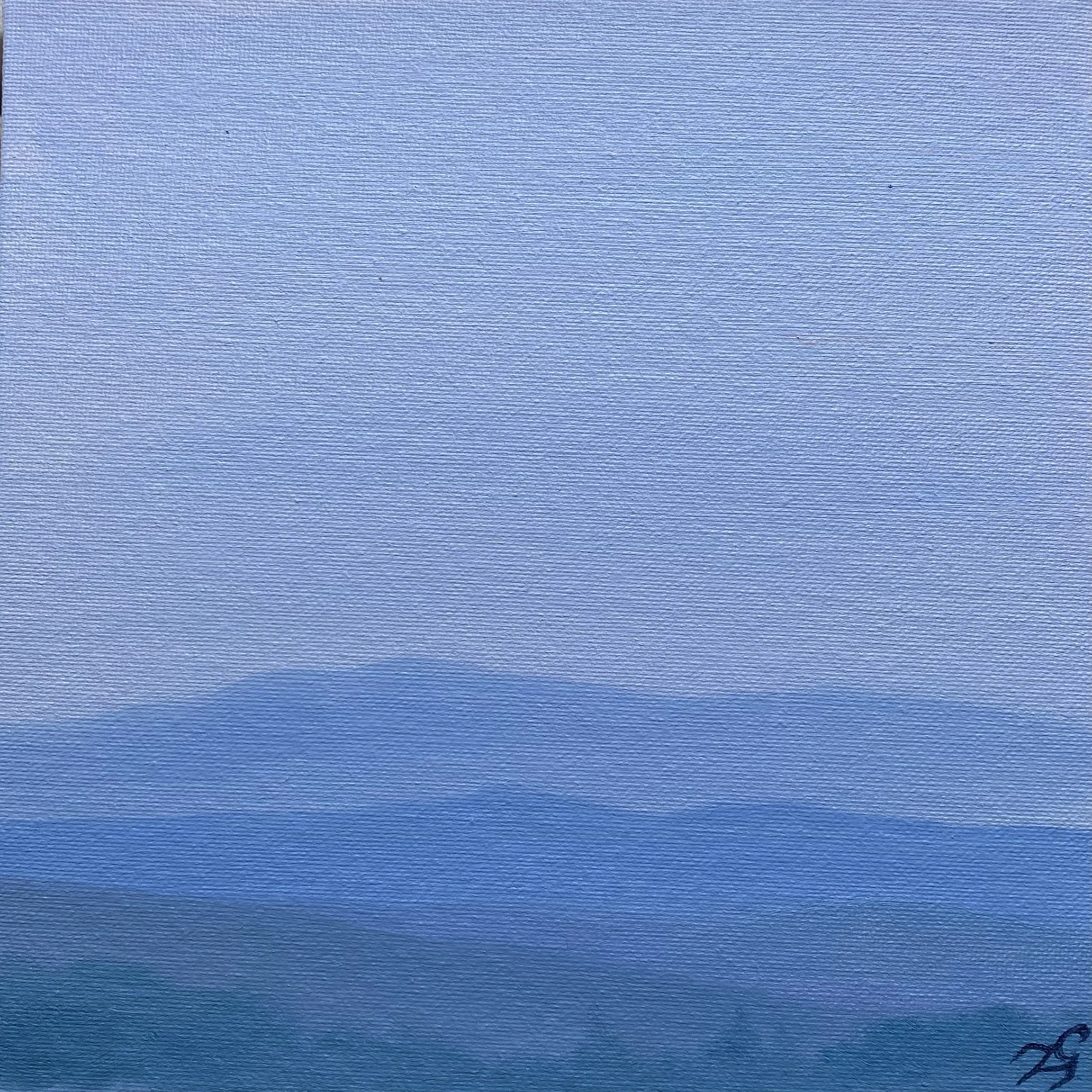 A cloudy sky over a calm body of water with mountains in the distance.