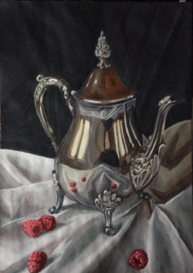 A reflective silver teapot with ornate handles and feet, placed on a wrinkled white cloth with scattered raspberries, against a dark background.