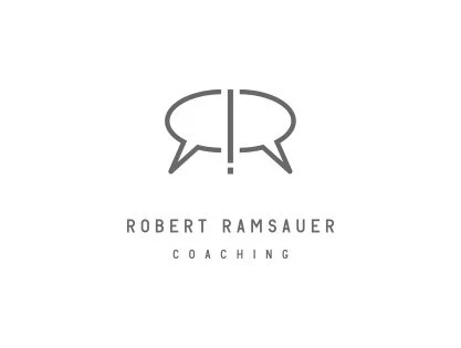 Logo mit zwei Sprechblasen, die einen Ausrufezeichenpfeil bilden, darunter der Name 'Robert Ramsauer' und die Wörter 'Coaching'.
