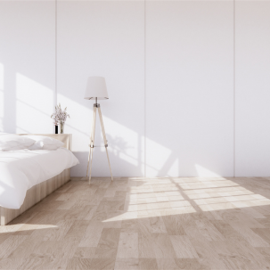 Minimalist bedroom with a bed, a bedside table with a vase of flowers, a floor lamp, and sunlight casting shadows on the wooden floor and white wall.