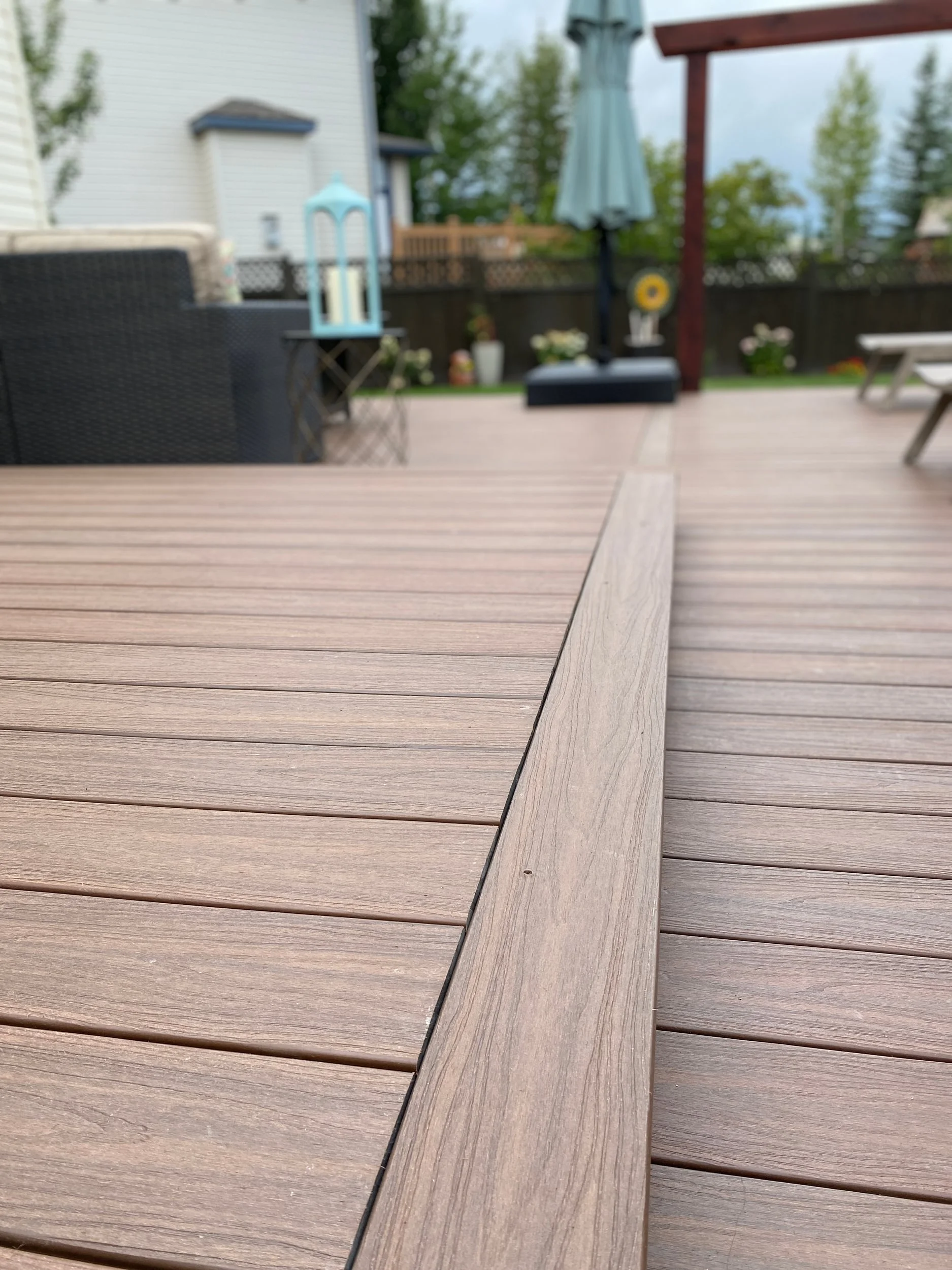 Close-up of a Northern Arbor deck with outdoor furniture and a backyard in the background.