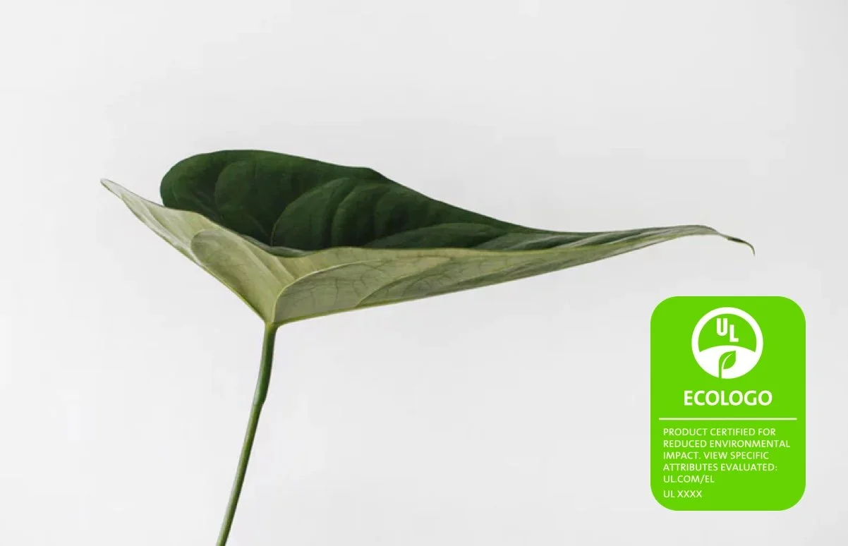 Une feuille verte, avec un côté clair et un côté plus foncé, sur un fond blanc. Un label écologique vert indique sa certification environnementale.