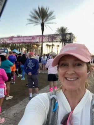 selfie of girl in pink ball cap and white shirt in front of a running race start line