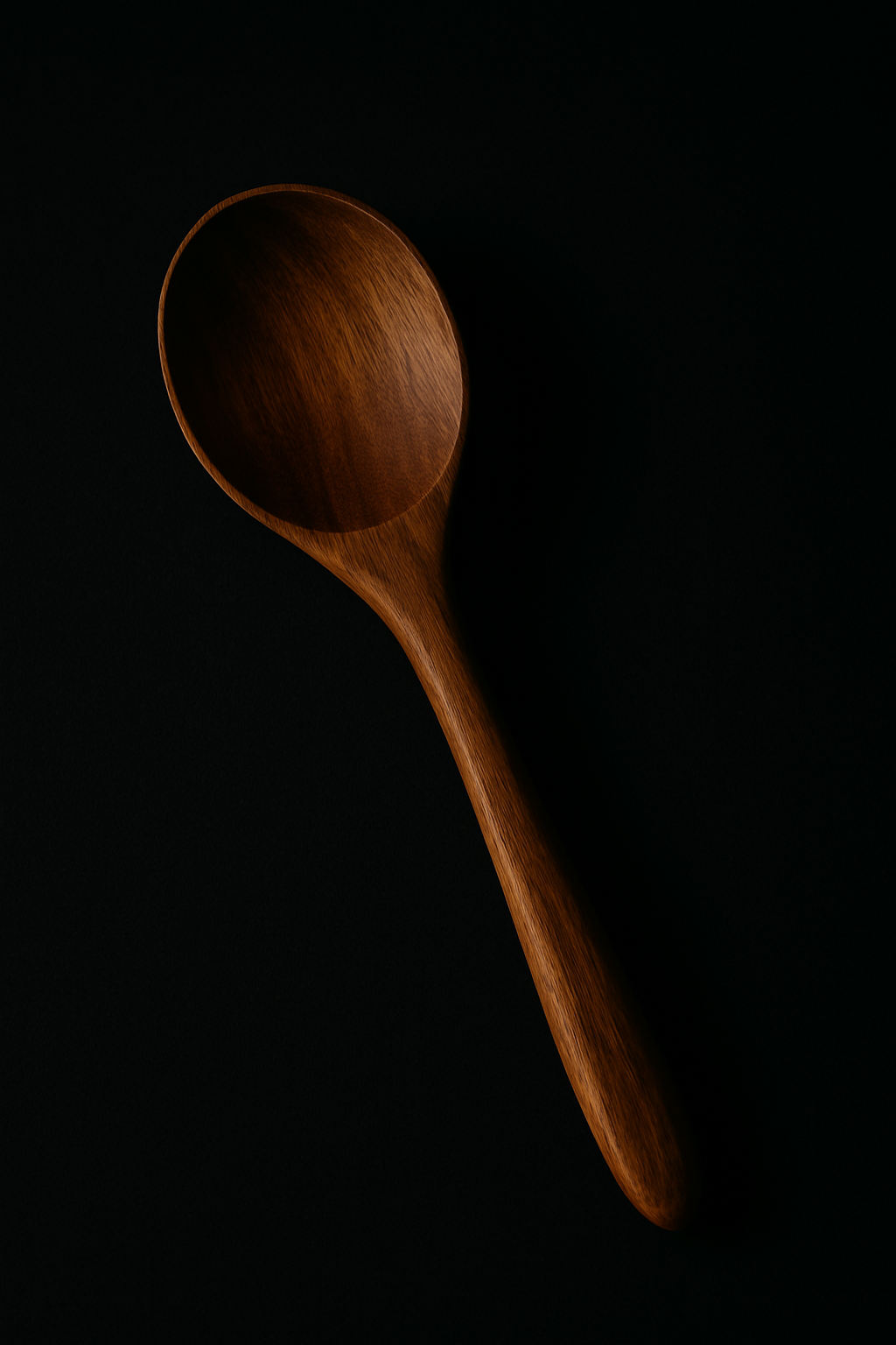 Minimalist flat-lay of a large wooden serving spoon styled on a dark black background.