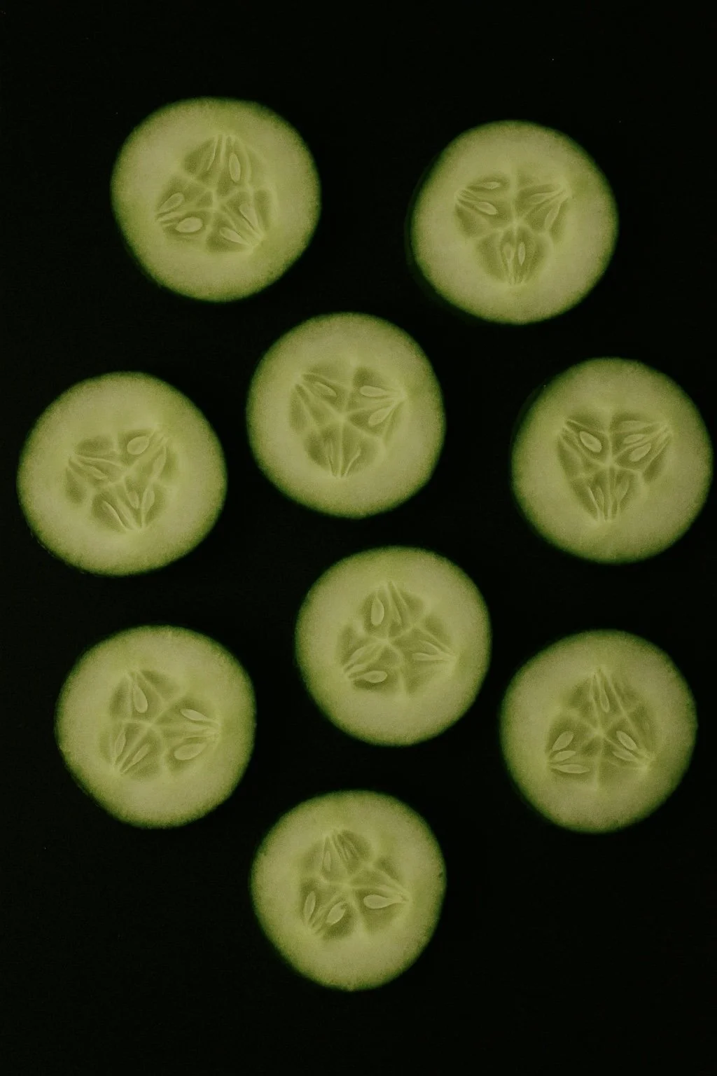 Slices of cucumber laying flat on a black background