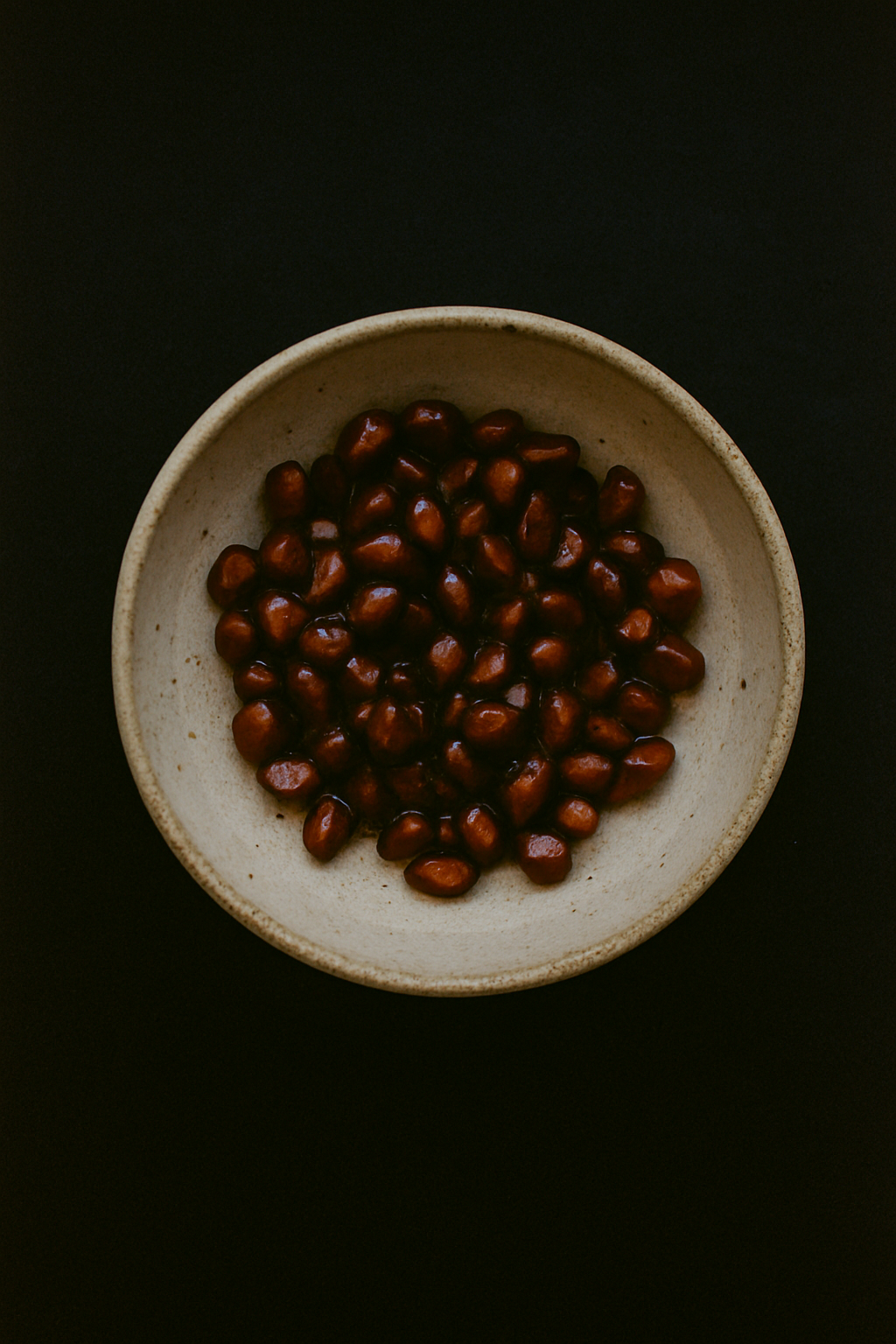 pomegranate seeds in a beige ceramic bowl on a black background