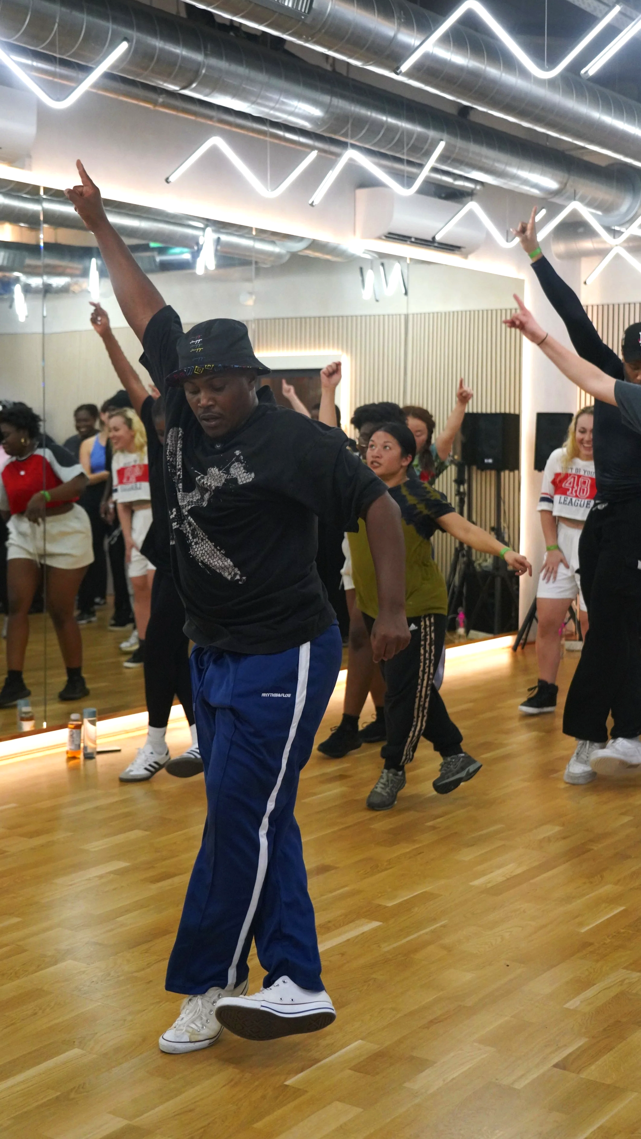 People participating in a dance class in a studio with wooden floors and modern lighting.