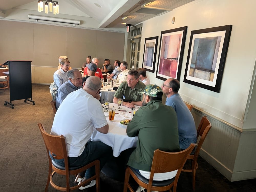 People sitting around a long dining table in a restaurant, engaged in conversation during a meal.