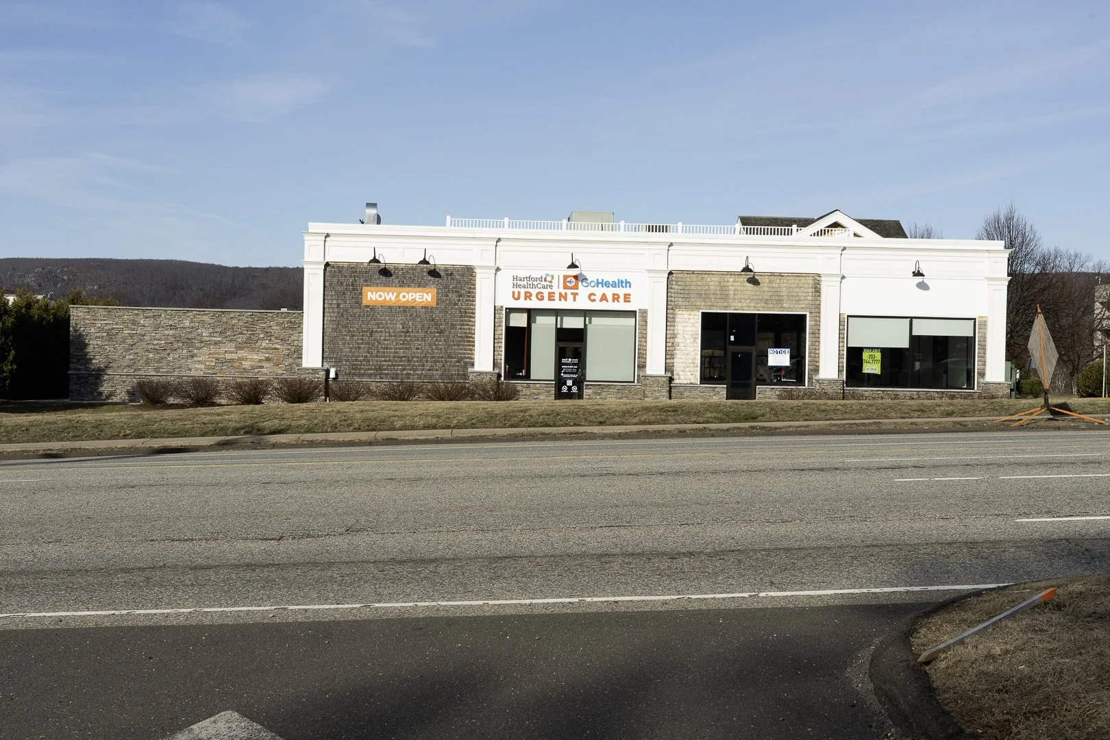 A storefront with a sign that says 'Now Open' and offers urgent healthcare services, part of Hartford Healthcare and GoHealth.