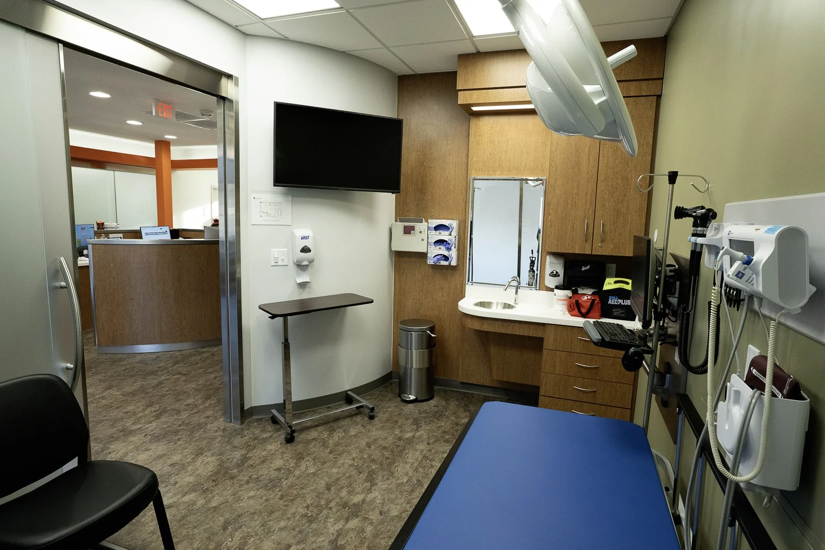 A medical examination room with medical equipment, a computer, and a patient bed.