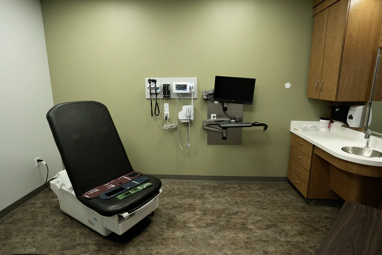 Doctor's examination room with medical equipment, examination chair, and a sink.