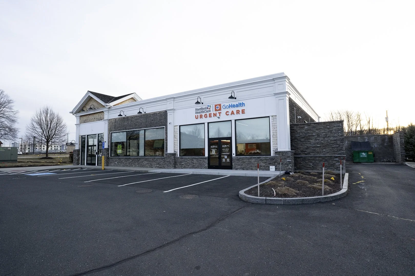 Exterior of an urgent care clinic with a parking lot in the foreground and a clear sky.