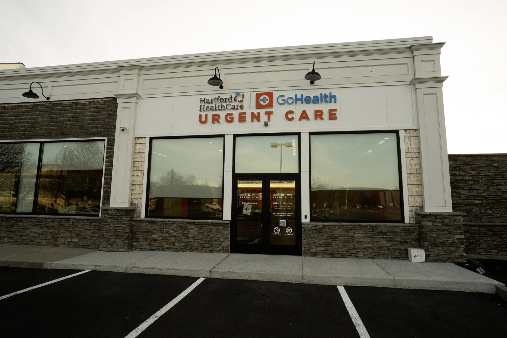 Front view of a healthcare building with signage for Hartford Healthcare, GoHealth, and Urgent Care, and parking spaces in the foreground.