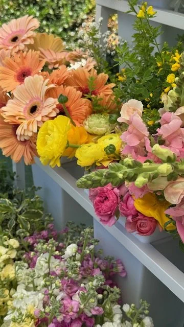Arrangement of colorful flowers including pink, orange, yellow, and purple blooms on display, bloom bar, flower bar, flower cart