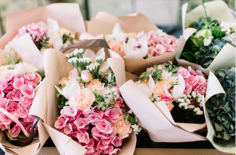Multiple bouquets of pink and white flowers wrapped in paper. Hand-tied bouquet, wrapped bouquet