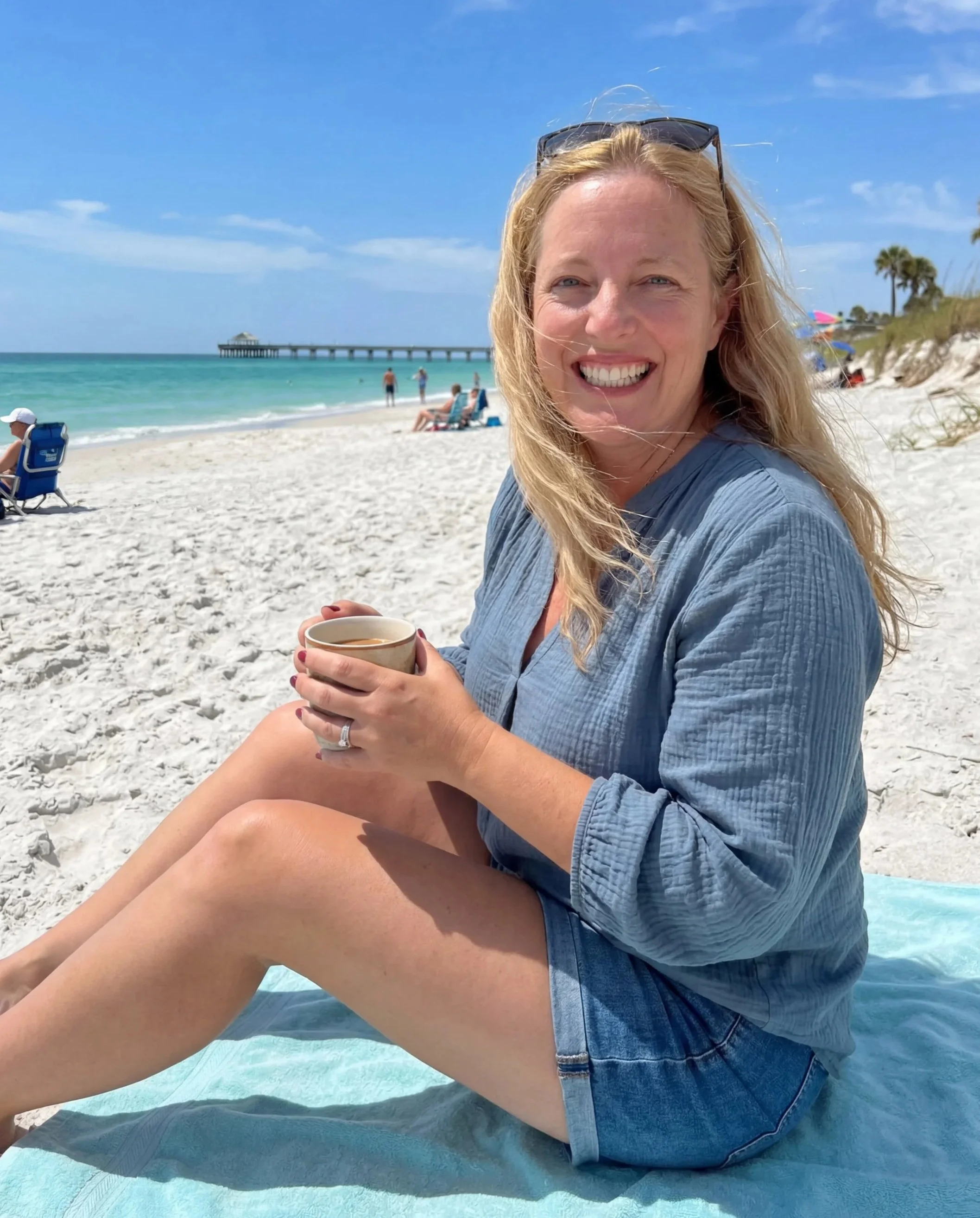 Kimberly Beckler, LMHC, sitting on the beach with a cup of coffee