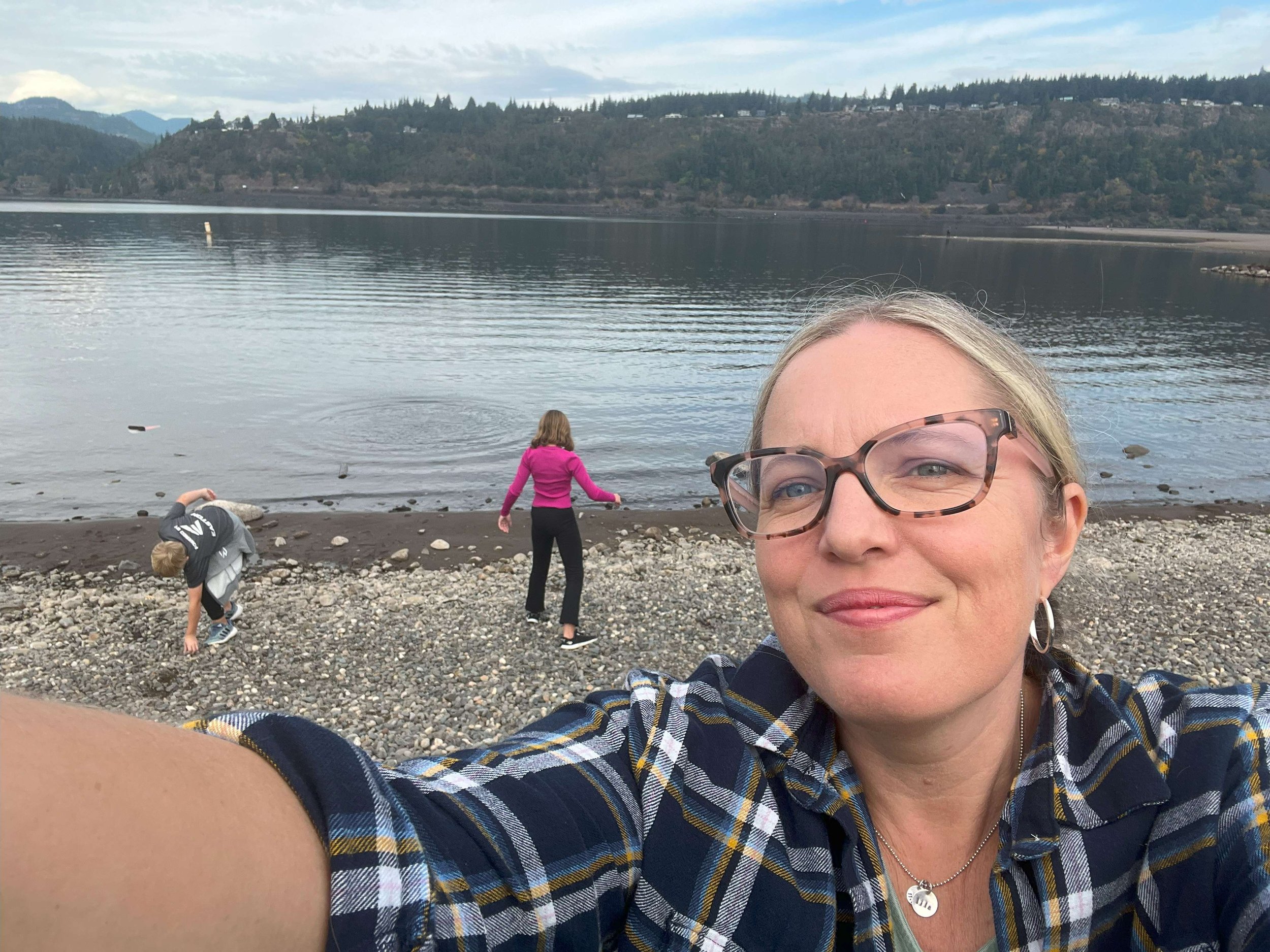 A woman, Kimberly Beckler, smiling by the ocean with a lake in the background.
