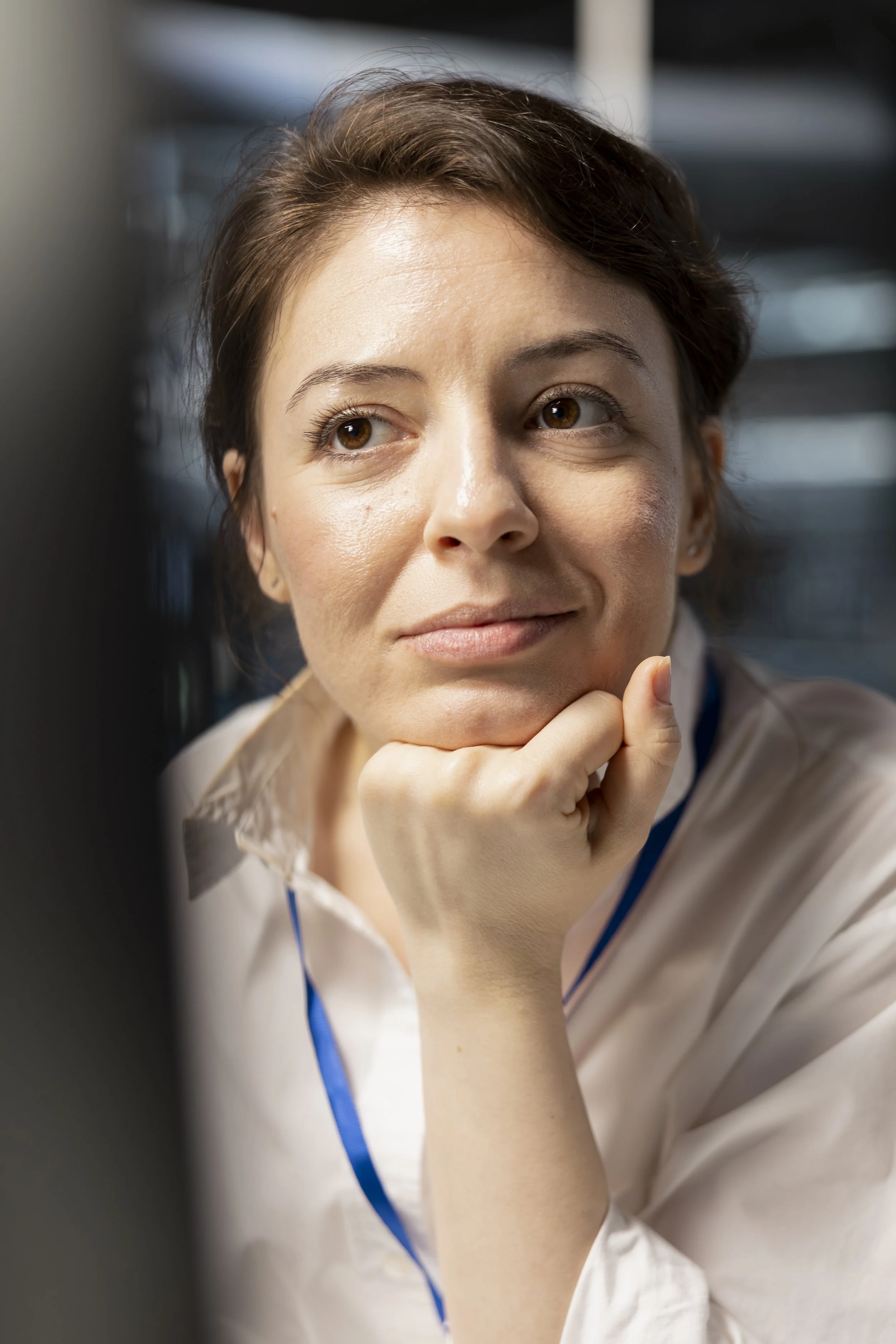 Close-up of a woman with short brown hair resting her chin on her hand