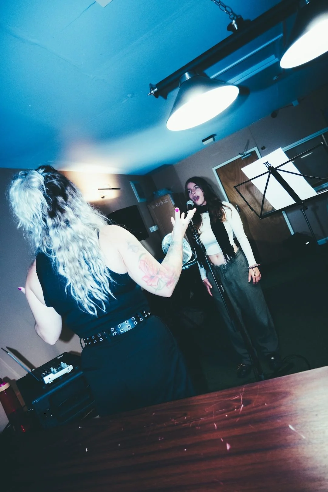 Two women singing, singing into a microphone. Singing Lessons Bideford, Music Teacher Bideford, Singing Lessons North Devon, Bold Note Vocal Coaching.