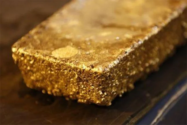 Lingot d'or massif posé sur une surface en bois