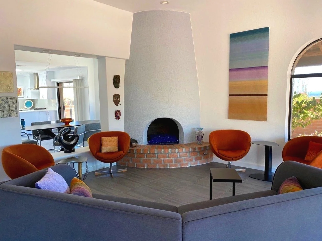 Sun-filled modern living space featuring an adobe style fireplace, a mix of craft objects d’art, and modern furniture.