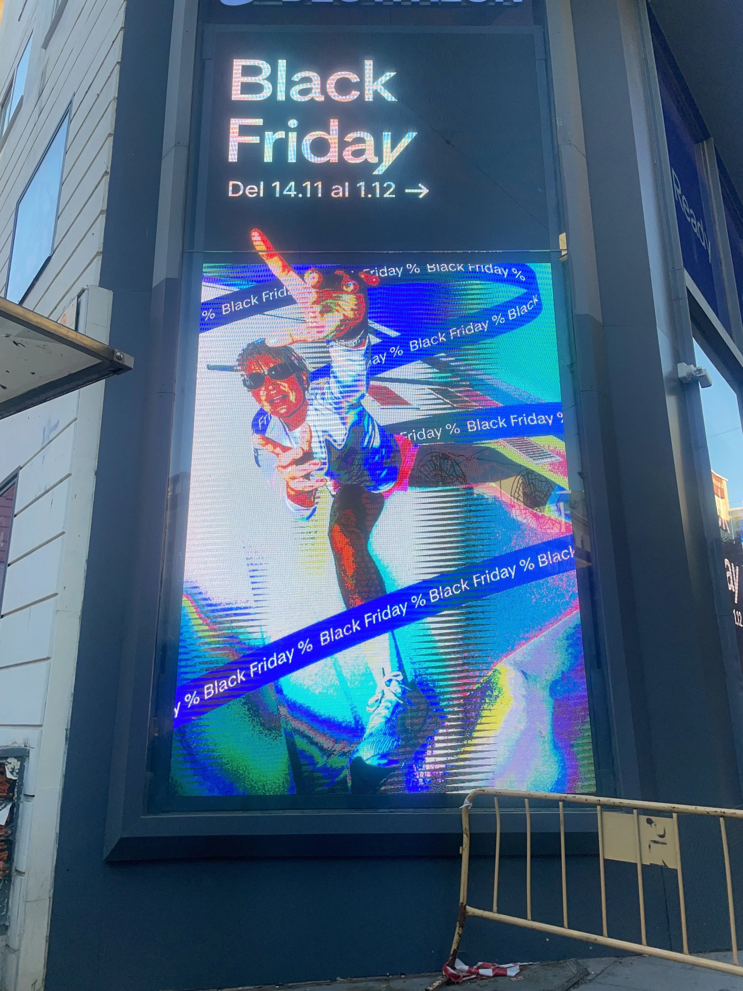 Digital billboard promoting Black Friday sales, displaying a colorful, stylized image of a person pointing with a rainbow-colored overlay, and text advertising the Black Friday sale from November 14 to December 1.