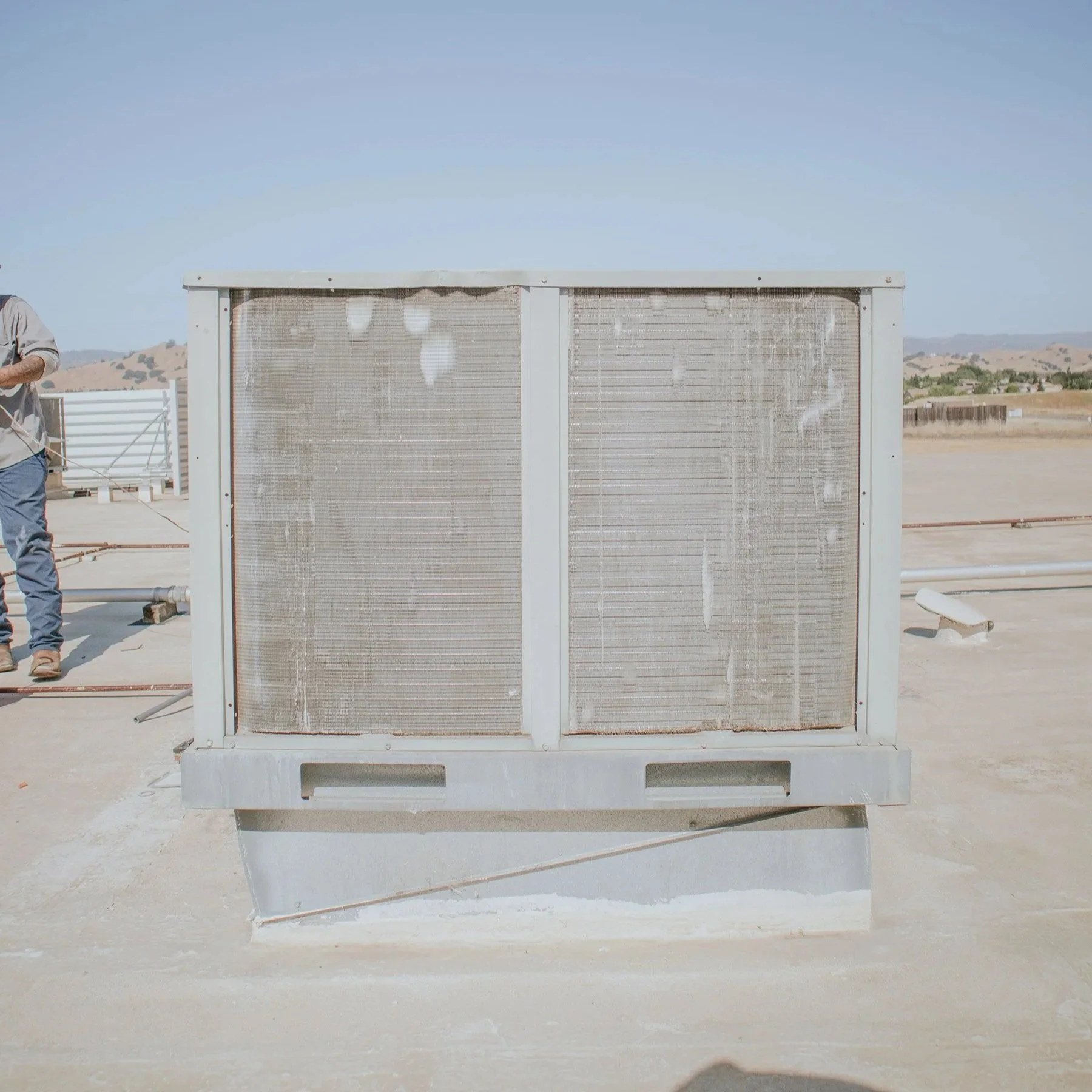 A large industrial air conditioning unit installed on a rooftop under a clear sky.