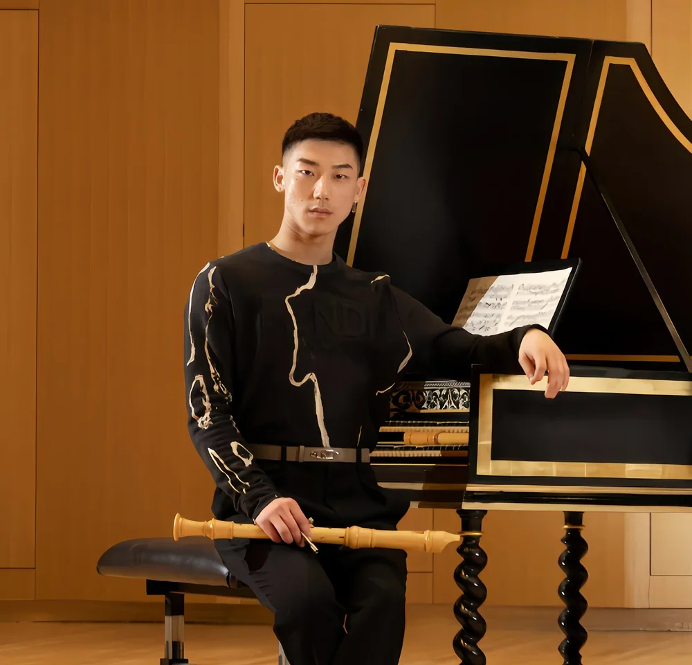 Peter Lim sits at a harpsichord holding a recorder