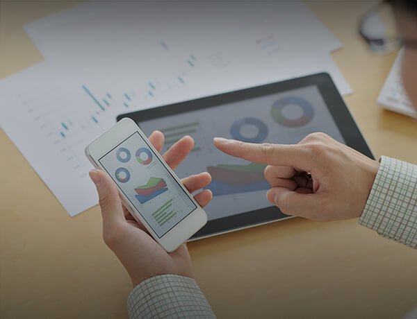 Person using a smartphone and a tablet to view financial data and charts.