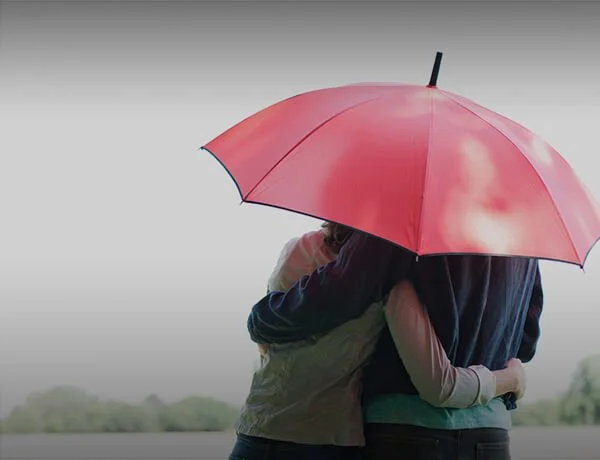 Two people holding an umbrella outdoors during rain.