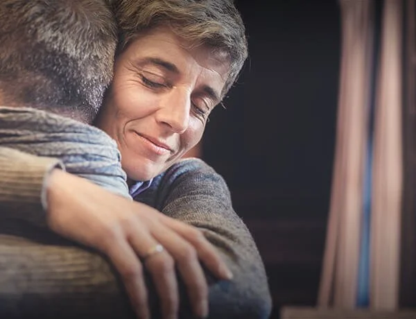 Two people hugging, smiling, and showing affection in a heartfelt moment.