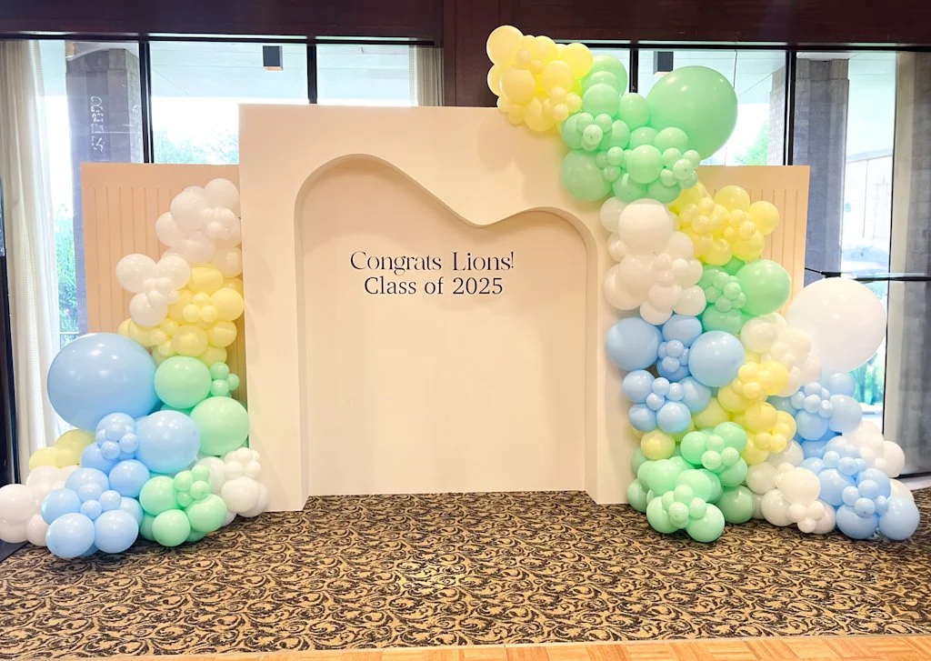 Decorative balloon arch and backdrop with a message that says "Congrats Lions! Class of 2025" for a celebration or graduation event.