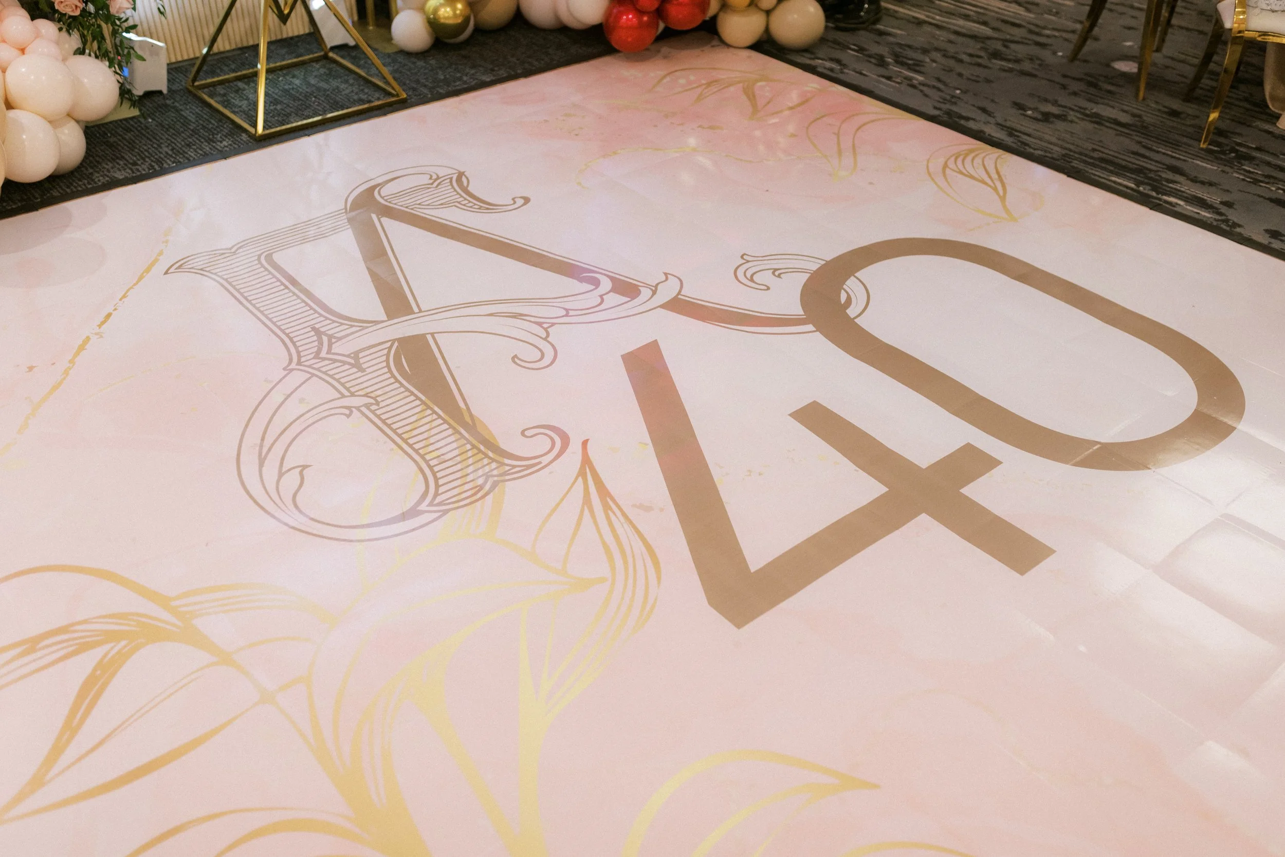 A light pink decorative floor banner with gold floral designs and the number 40 in large gold font, likely for a 40th birthday celebration.