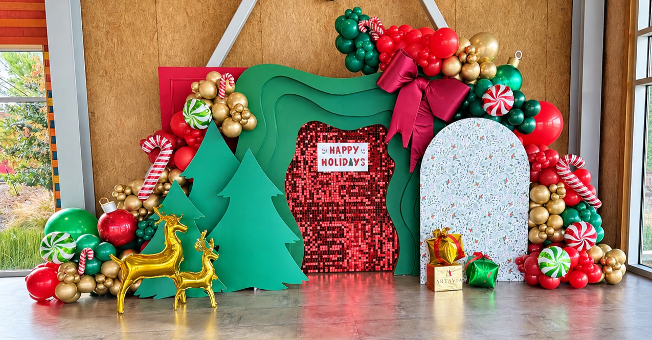 Green and red holiday backdrop with a red shimmer panel, balloon garlands, candy canes, tree cutouts, and gold reindeer.