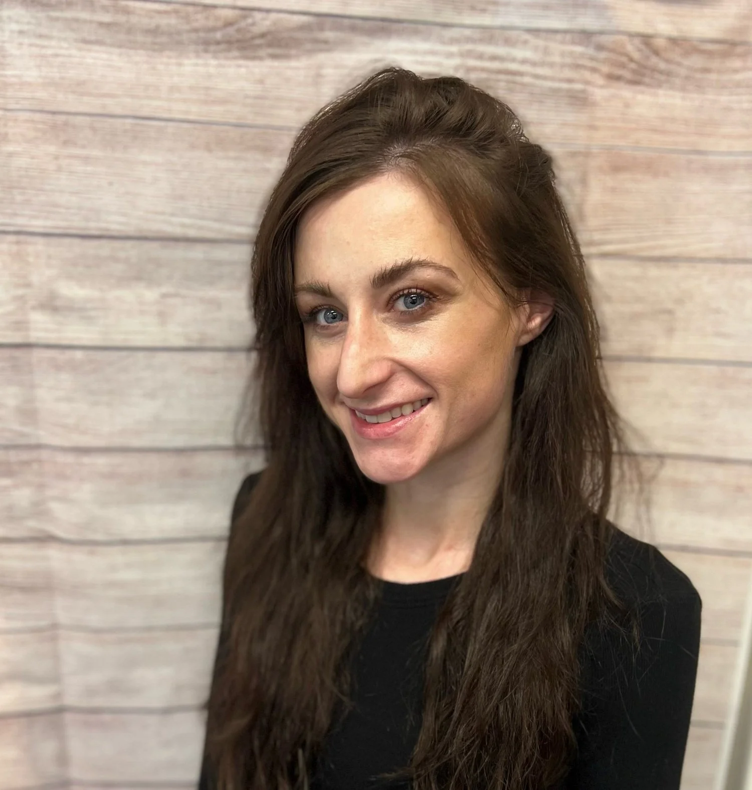 Jill Costello smiling in professional portrait against light wooden backdrop, representing Cocoon House team in Snohomish County