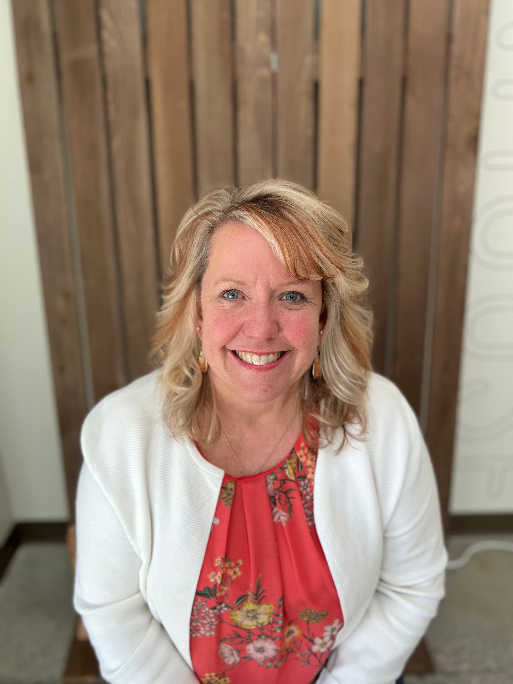 Board member with blonde hair smiling in portrait against wooden wall, Cocoon House Snohomish County