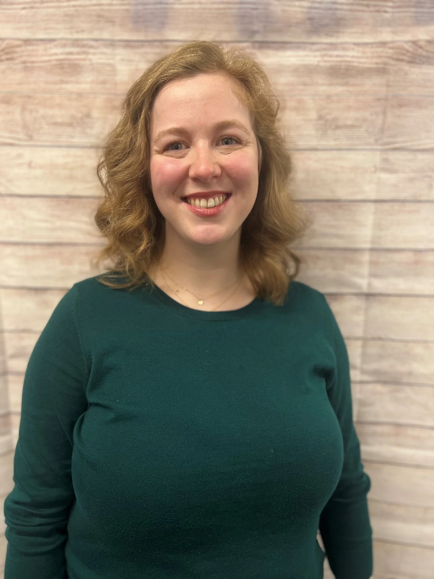Claire Petersen smiling in professional portrait against light wooden backdrop, representing Cocoon House team in Snohomish County